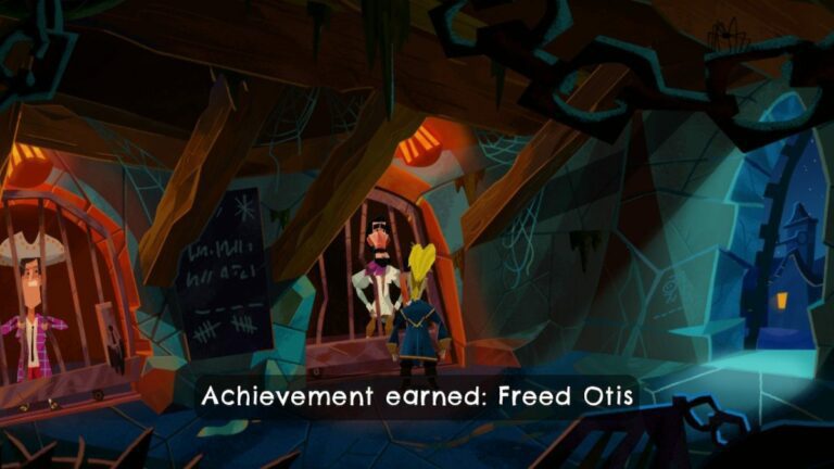 a dank, dimly lit jail call. a man in a white shirt with a dark beard stands behind jail cells bars while Guybrush peers at the lock on the cell door. Wood beams stretch from the walls to the ceiling. another man in a large hat stands in the next cell over