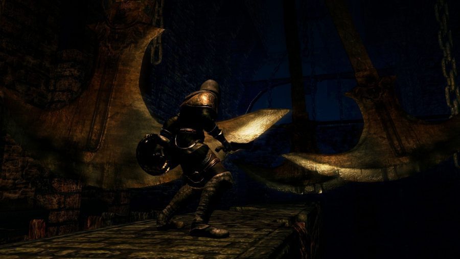 Um personagem de Dark Souls atravessa uma passarela com machados balançando acima dela.