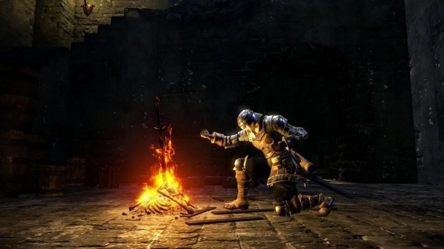 Um personagem de Dark Souls se ajoelha com um braço estendido sobre uma fogueira.