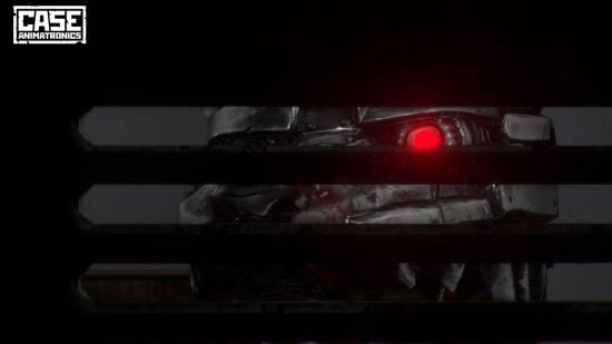 FNAF fan games: Um animatrônico de metal prateado com olhos vermelhos brilhantes olhando para o espectador através de um painel com fenda em uma tela escura, sugerindo que o espectador está escondido em um armário.  O logotipo da Case Animatronics está no canto superior esquerdo da imagem.