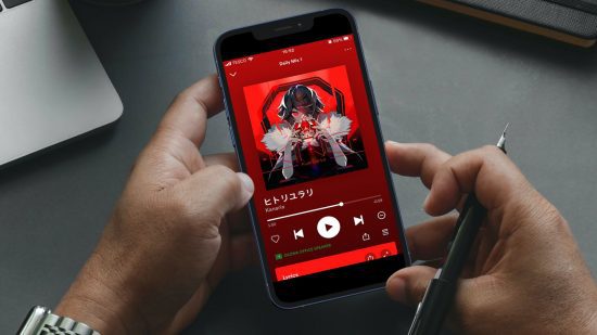O que é o Spotify: uma foto de um par de mãos segurando um smartphone.  O telefone está mostrando a tela do player de música Spotify tocando King by Kanaria.