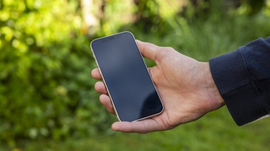 O iPhone 12 nas mãos de um homem sob o sol