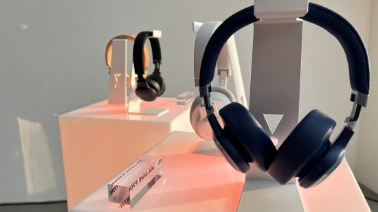 jbl soundgear sentido 2 um fone de ouvido JBL colocado em um suporte transparente com uma mesa rosa abaixo