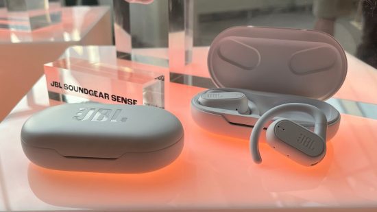 jbl-soundgear-sense-review-2 Imagens de análise do JBL Soundgear Sense mostrando um case oval próximo em uma mesa vermelha e branca ao lado de uma aberta com dois fones de ouvido à mostra.