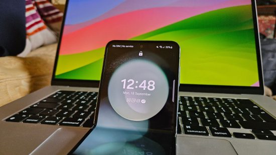 melhores telefones flip-galaxy-z-flip5 Os melhores telefones Flip - uma imagem mostrando a parte superior de um Galaxy Z Flip5 com a hora em um fundo abstrato verde na frente de um laptop